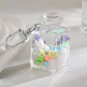 Macro shot of liquid-filled square bottle pendant with macaron beads and lobster clasp