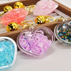 Close-up of heart-shaped glitter keychains with liquid oil, beads, and golden bells