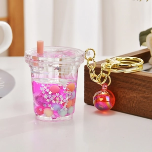 Macro detail of boba tea keychain featuring purple liquid, glitters, and gold metal ring