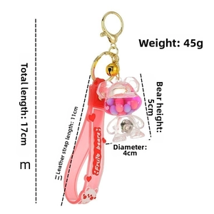Detail of pink liquid bear keychain with internal colorful balls and gold metal hardware