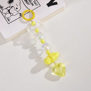 Detail of yellow beaded bag charm featuring acrylic bow, cloud, and heart pendants
