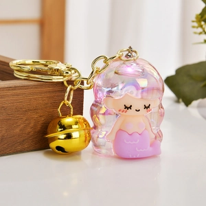 Detail of mermaid keychain featuring iridescent shell, golden bell and metallic hook