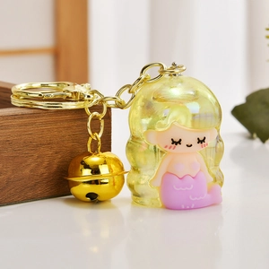 Macro detail of acrylic mermaid keychain with translucent yellow shell and golden bell