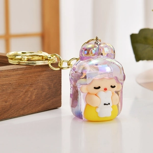 Cute girl keychain with yellow dress and iridescent hair leaning on a wooden edge