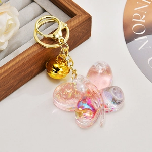 Detail of pink acrylic butterfly keychain with glitter, sequins and golden bell charm