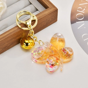 Detail of butterfly oil-filled acrylic keychain with gold sequins and charms