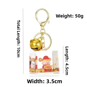 Macro detail of God of Wealth keychain with liquid gold sand and bell on white background