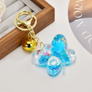 Detail of butterfly liquid glitter keychain with blue oil and golden bell charms