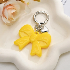 Detail of yellow acrylic bow keychain with heart pendant and metal spring clip on tray