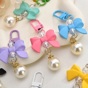 Colorful macaron bow pendants with pearls and rhinestones shown on a ceramic tray