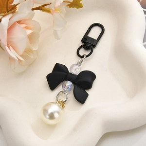 Detail of sweet black matte bow keychain with large white pearl and iridescent beads