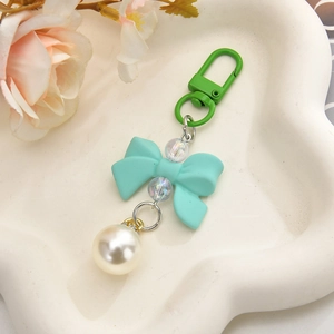 Detail of sweet mint green bow keychain with white pearl pendant and colorful beads