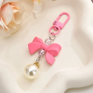 Detail of pink bow pendant with pearls and colorful beads in a white heart tray