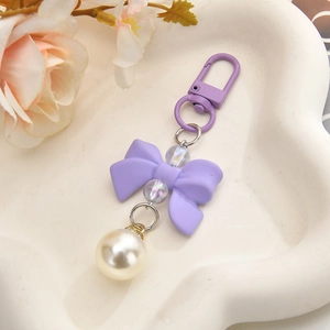 Sweet purple bow keychain with pearls and lobster clasp on a white heart plate