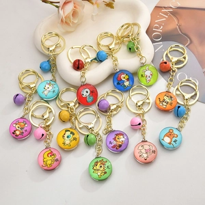 Set of 12 cartoon zodiac keychains with colorful bells and glass charms on a white tray