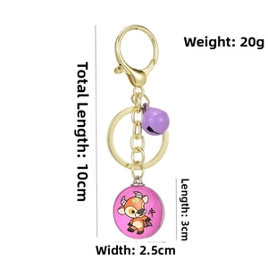 Detailed view of a 3D zodiac cow keychain with purple bell and pink logo pendant
