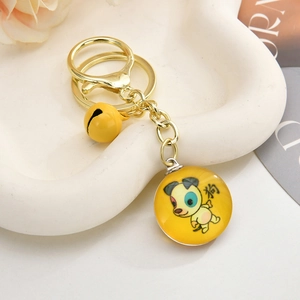Detail of a golden dog zodiac keychain with bell and lobster clasp on floral tray