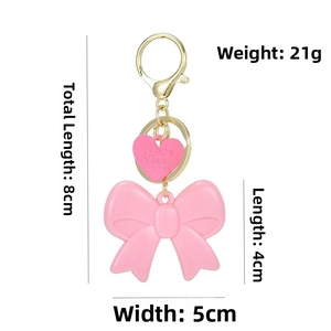 Detailed view of pink acrylic bow keychain with gold lobster clasp and heart charm