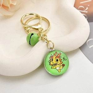 Detail of 3D dragon keychain with green bell and lobster clasp on ceramic plate