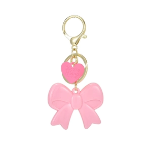 Pink acrylic bow keychain with gold heart tag and metallic clasp for backpacks