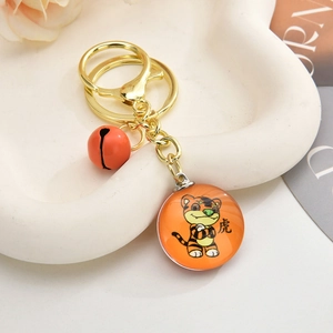 Detail view of cartoon tiger keychain with gold ring, orange bell, and glass charm pendant