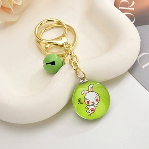 Detail of a 3D rabbit keychain with golden ring, green bell and cartoon pendant