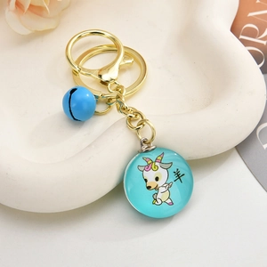 Macro shot of 3D zodiac sheep keychain with blue bell on white ceramic tray