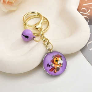 Close-up of a purple zodiac horse keychain with gold metal chain and small purple bell