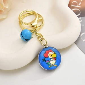 3D cartoon rooster keychain with blue bell and golden ring on a white plate