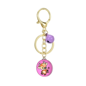 Detail of golden metal keychain with pink zodiac ox pendant and purple bell accessory