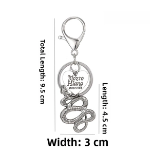 Silver metal snake keychain detail showing textured scales and engraved heart charm tag