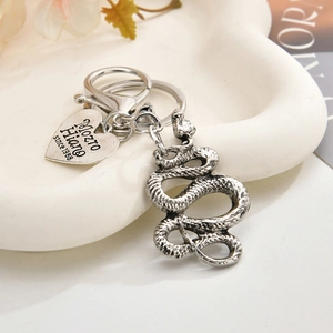 Macro view of silver skull keychain with snake pendant and engraved heart charm detail