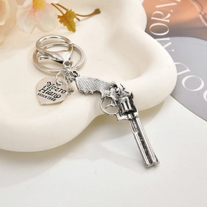 Detail of vintage silver revolver keychain with heart charm on a decorative tray