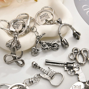 Detailed collection of vintage silver skull and motorcycle metal keychains on a white tray