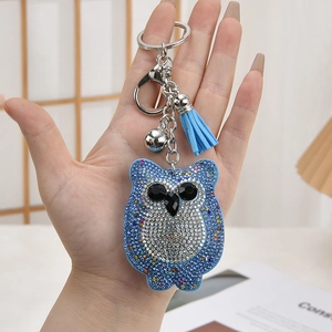 Sparkling blue owl rhinestone keychain with suede tassel and silver bell held in hand