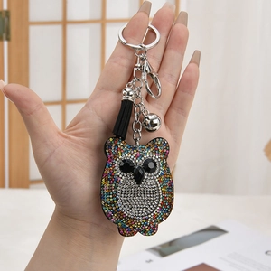 Sparkling owl rhinestone keychain with black tassel and bell held in hand