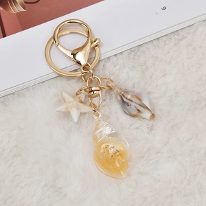 Detail of creative starfish and conch seashell keychain charms on soft white texture
