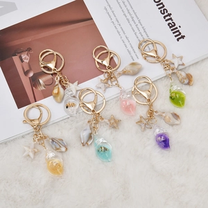 Five assorted seashell and starfish keychains in vibrant summer ocean theme colors