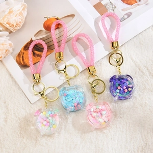 Close-up of four acrylic liquid keychain pendants with colorful beads and glitter straps