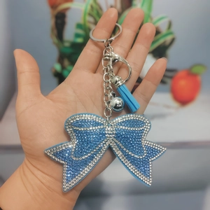 Close-up of a sky blue bow keychain with rhinestones, leather tassel and small silver bell