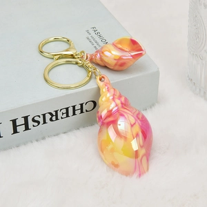 Detail of colorful seashell keychain with marble texture on blue book and white faux fur
