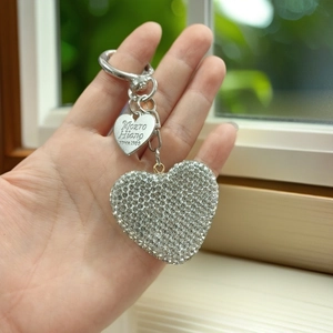 Close-up of sparkling rhinestone heart keychain with silver metal clasp and logo tag