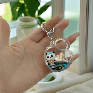 Detail of heart-shaped panda keychain with blue glitter sand and donut charms