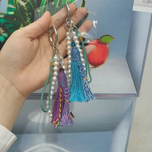 Detail of handmade colorful tassel charms with pearl chains and metal rings for bags