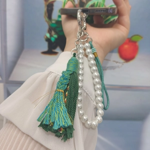 Detail of bohemian handmade green gradient silk tassel and white pearl beaded charm
