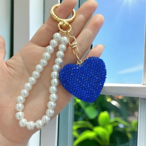 Detail of blue rhinestone heart keychain with elegant white pearl bead chain and gold clasp