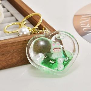 Macro view of heart-shaped acrylic oil keychain with floating green bunny and white pearls