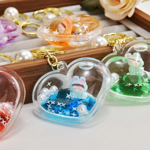 Close-up of heart-shaped acrylic liquid keychains with glitter and cartoon figures