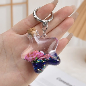Detail eines sternförmigen Treibsand-Schlüsselanhängers mit rosa Muscheln und Pailletten