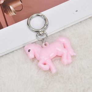 Pink acrylic horse keychain with silver metal ring on white plush background
